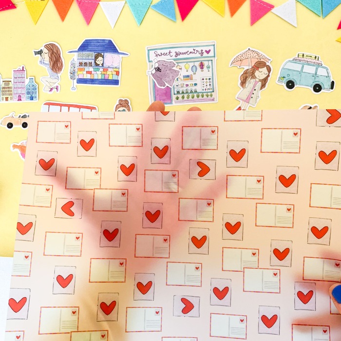 Papel decorativo com padrão de cartas postais e adesivos coloridos sobre fundo amarelo