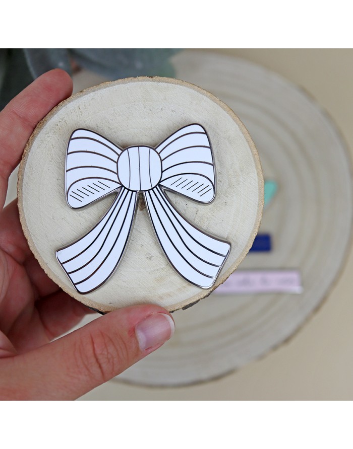 Broche laço branco com linhas pretas sobre disco de madeira