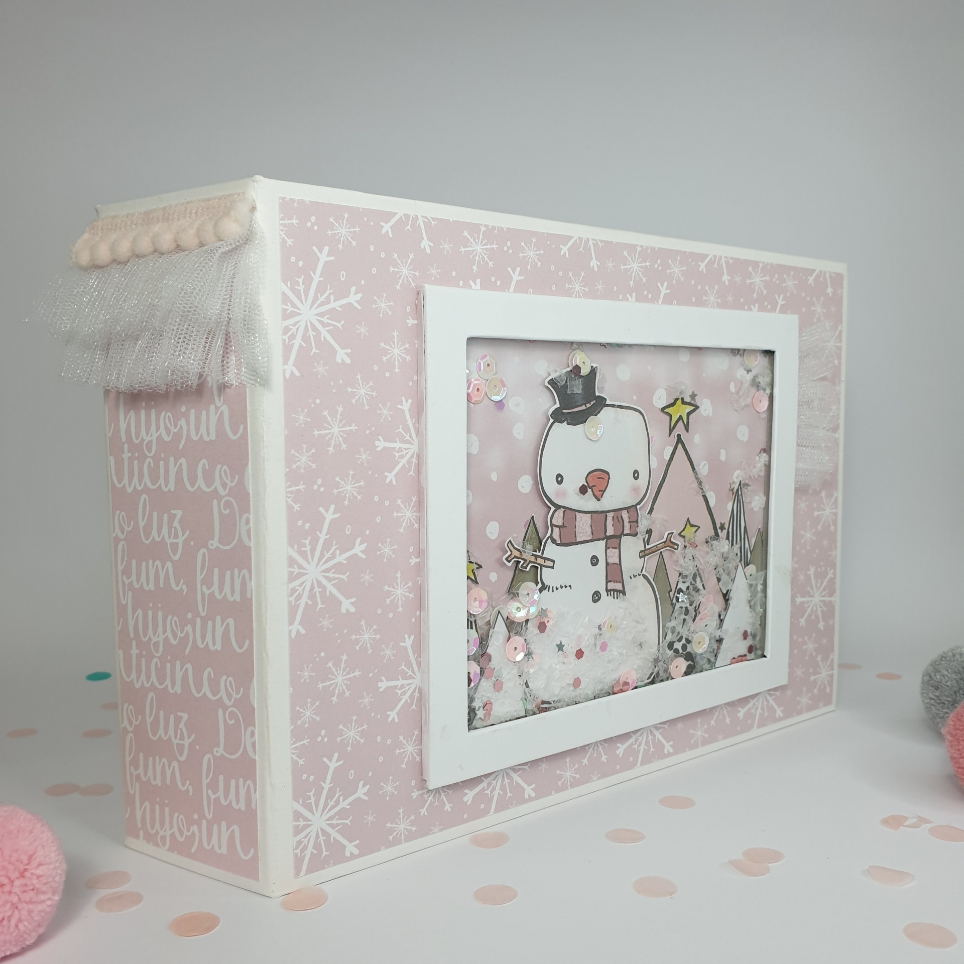 Caixa decorativa rosa com boneco de neve em janela frontal e detalhes de pompons e renda