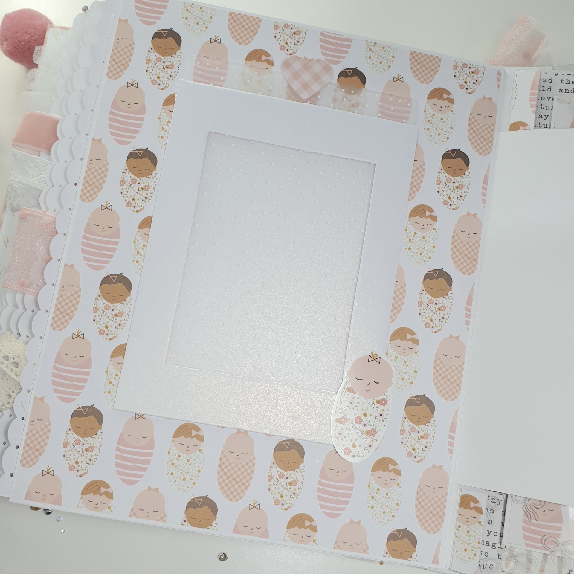 Álbum decorado com padrão de bebés em tons de rosa e bege com recorte para foto