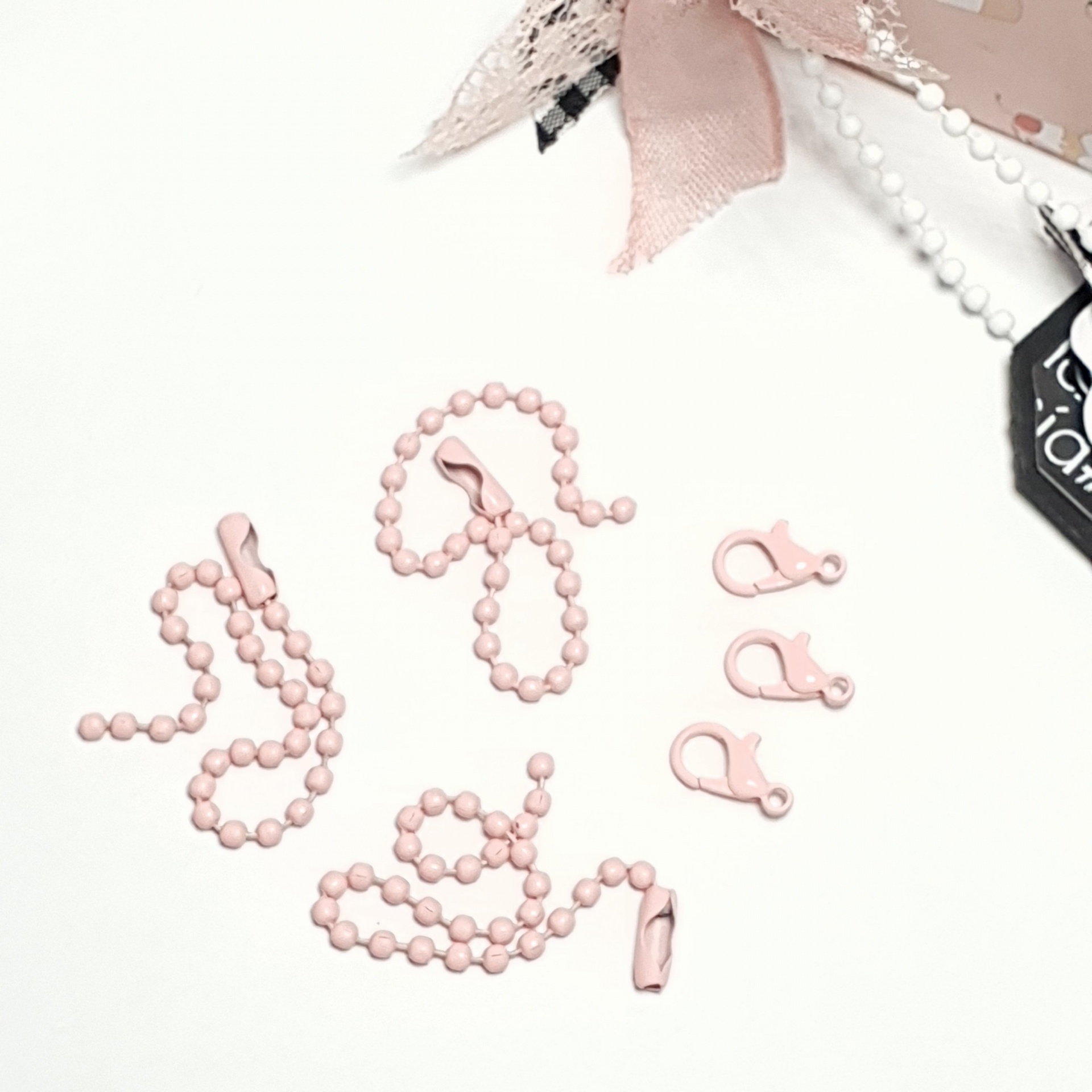 Três correntes de bolas rosa com fechos e três fechos adicionais cor-de-rosa sobre fundo branco