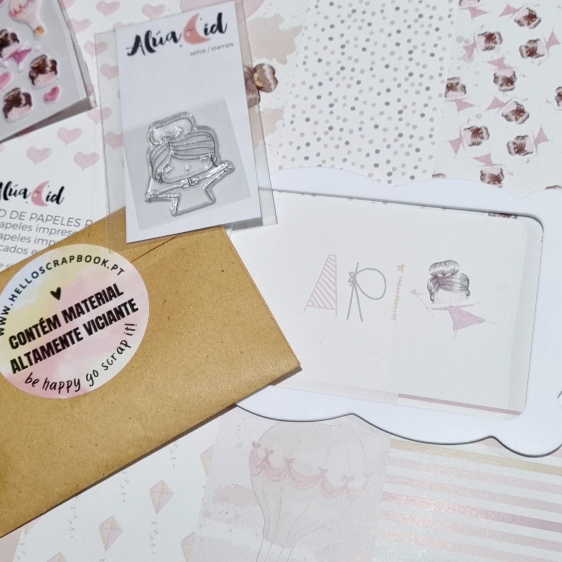 Materiais de scrapbooking com carimbo de mulher desenhadora, folhas decorativas e envelope castanho com selo redondo