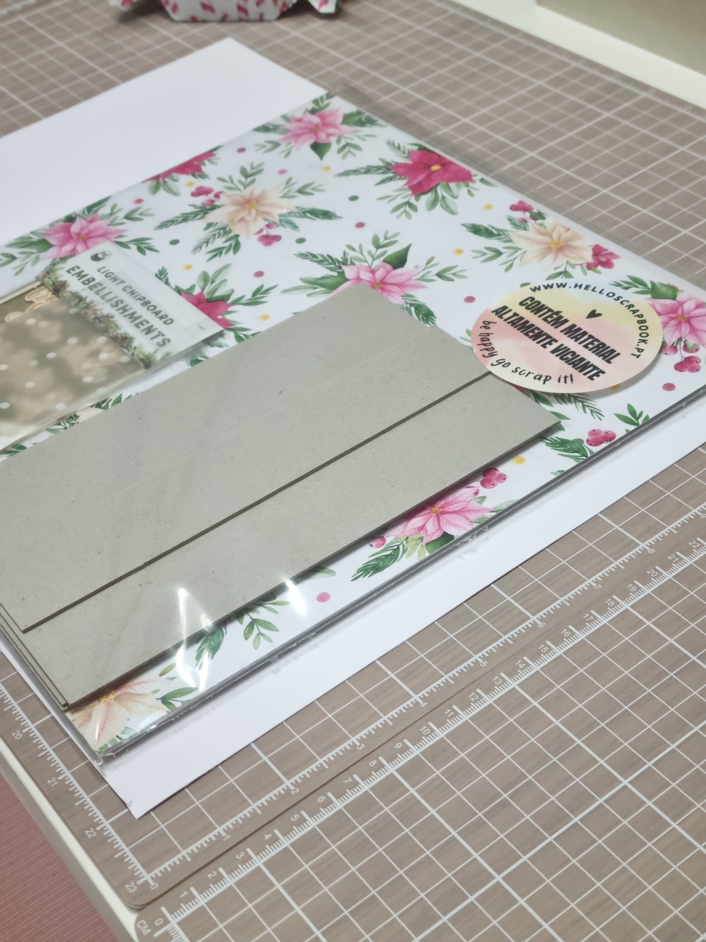 Kit de decoração para scrapbooking com papel floral e papel cinza em mesa de corte quadriculada