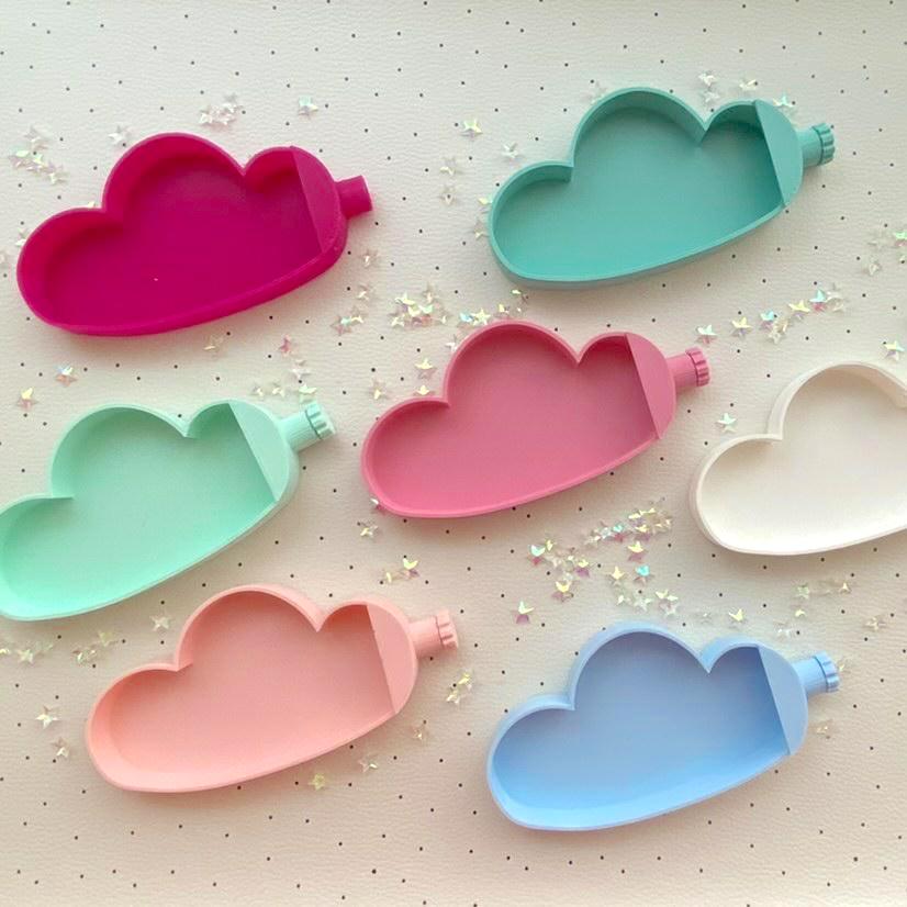 Formas de silicone em forma de nuvem coloridas sobre superfície clara com estrelas brilhantes.