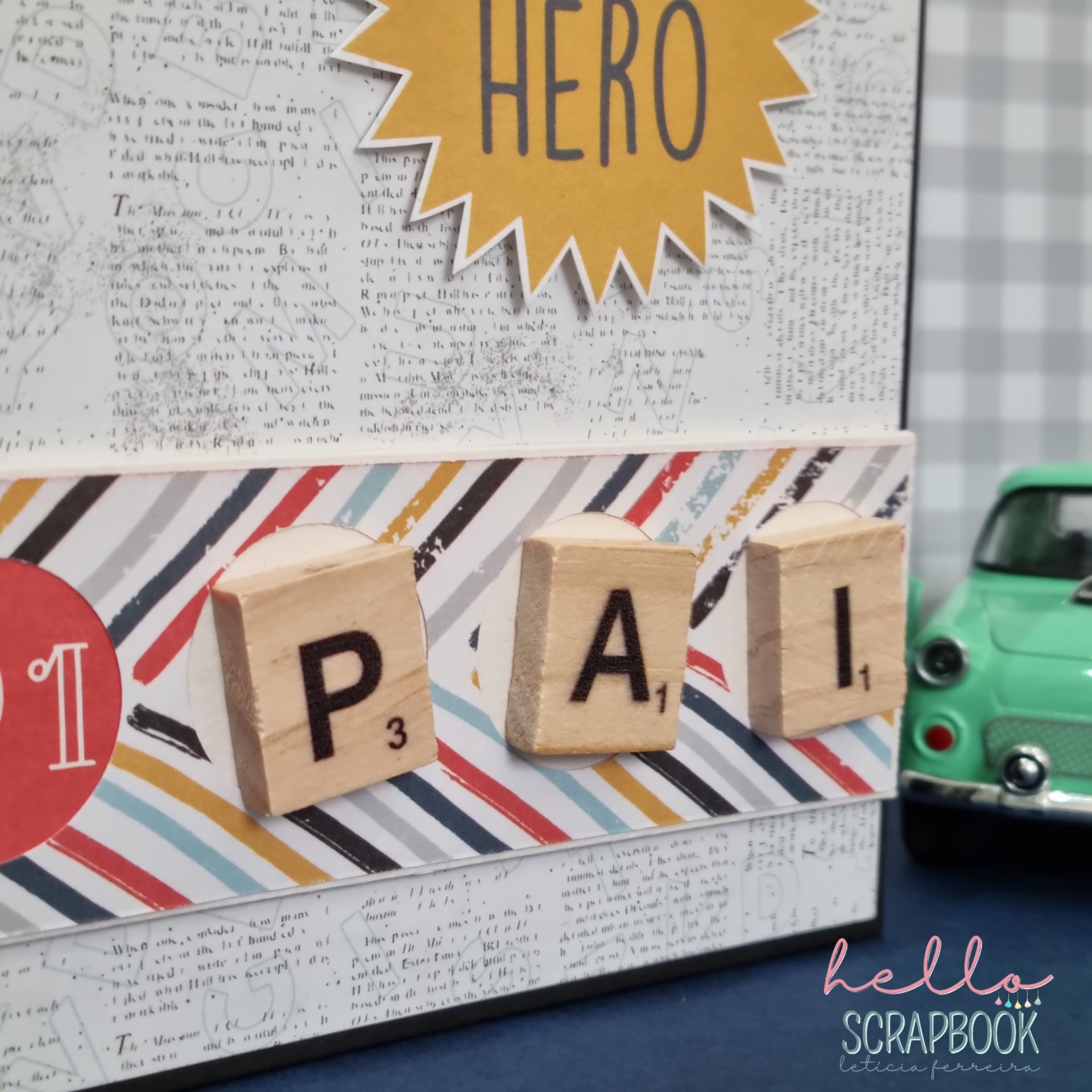 Scrapbook com letras de madeira formando PAÍ e miniatura de carro verde ao lado