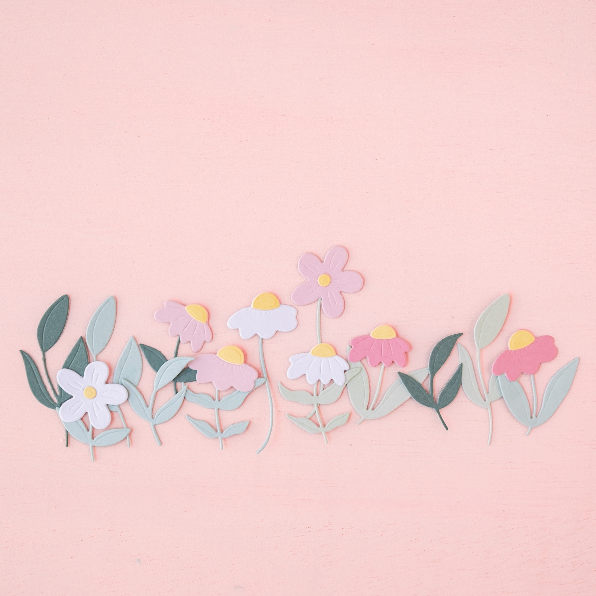 Flores decorativas em papel de várias cores sobre fundo rosa