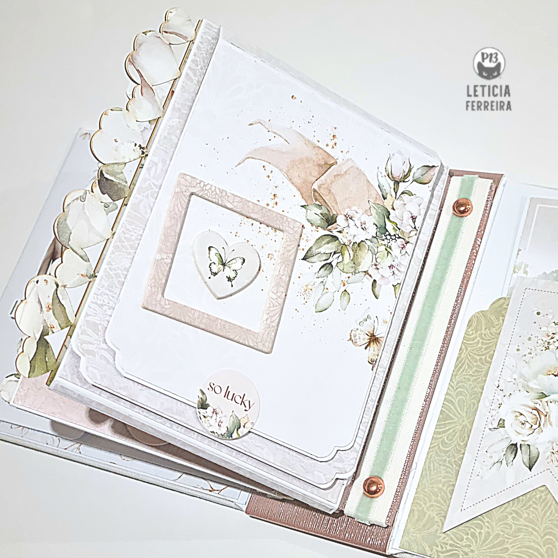 Álbum decorativo com flores em tons pastel e elementos de papel recortado com texto SO lucky