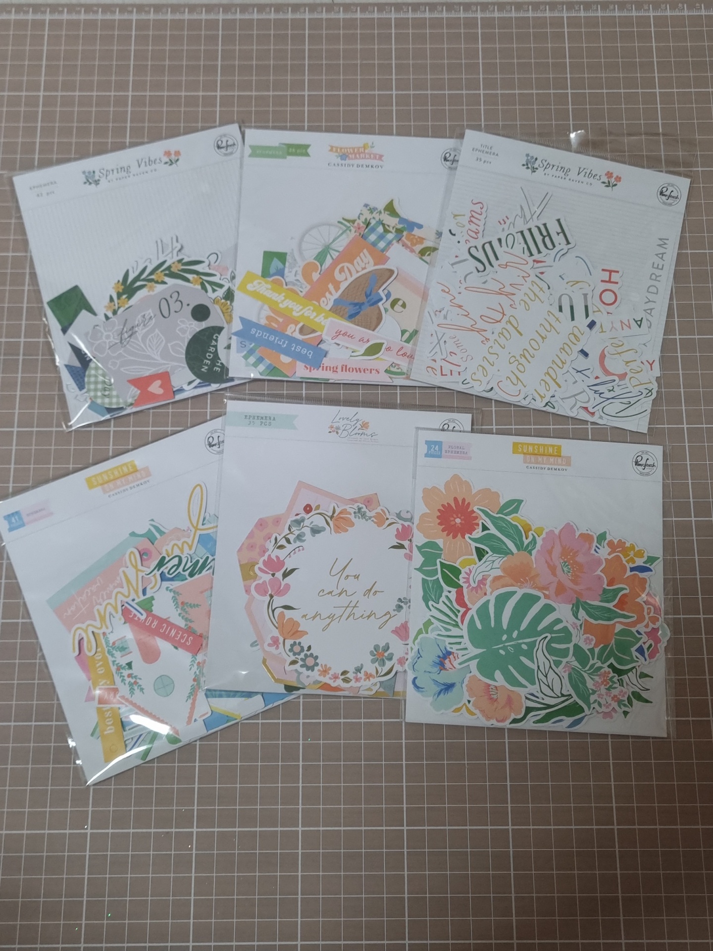 Pacotes de elementos de papel para scrapbooking com temas florais sobre superfície quadriculada