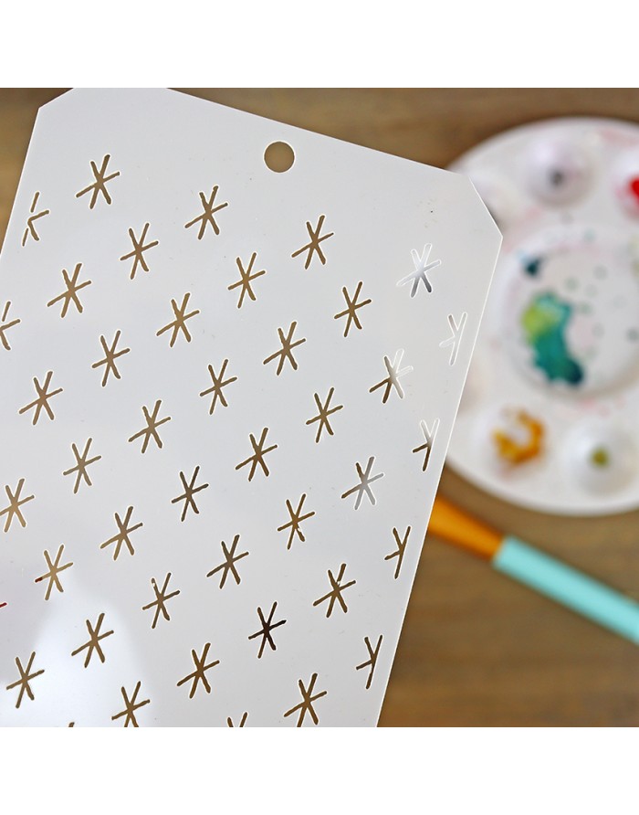 Folha branca com padrões dourados e prateados, paleta de pintura e pincel ao fundo