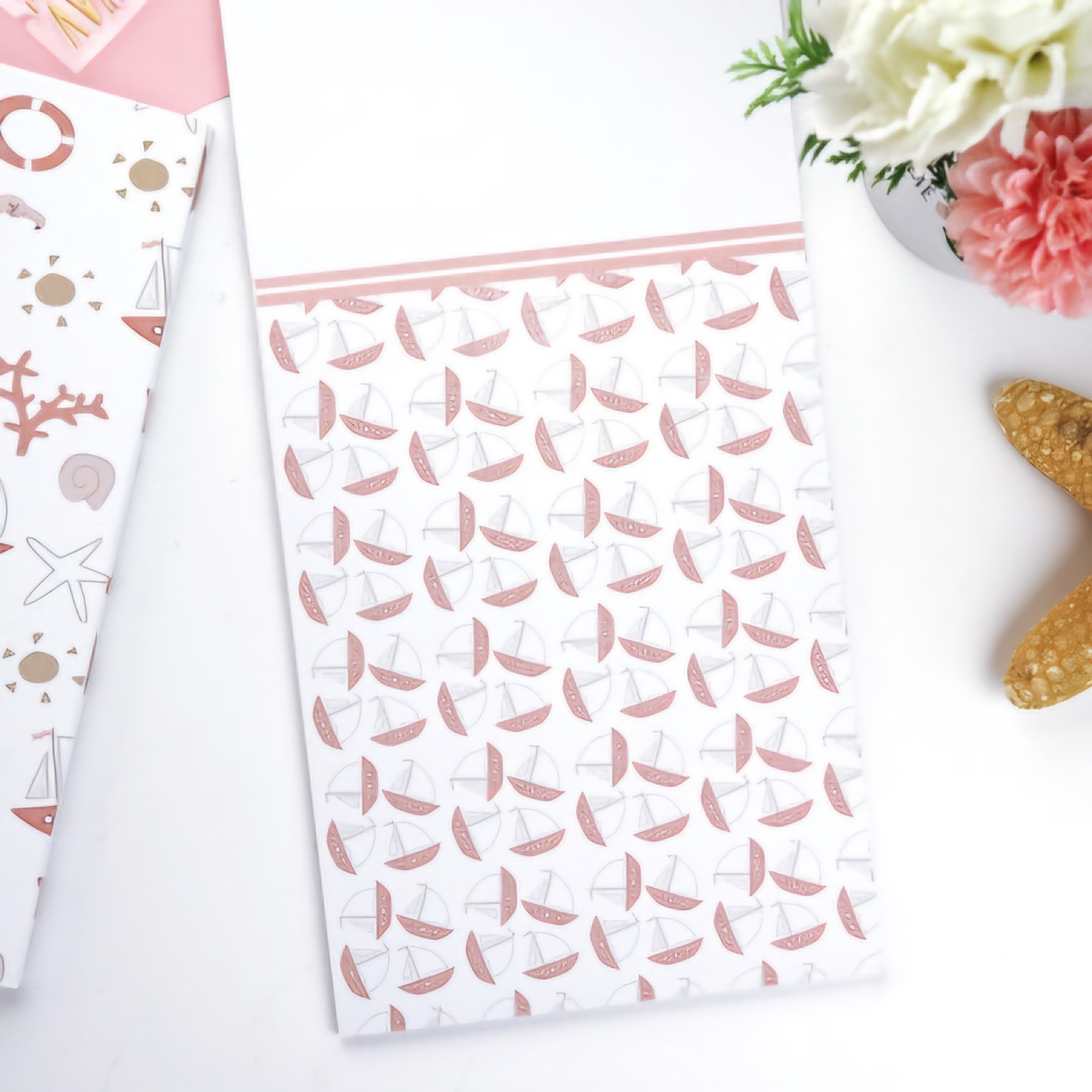 Caderno branco com padrão de velas rosa e cinza e barra rosa na parte superior