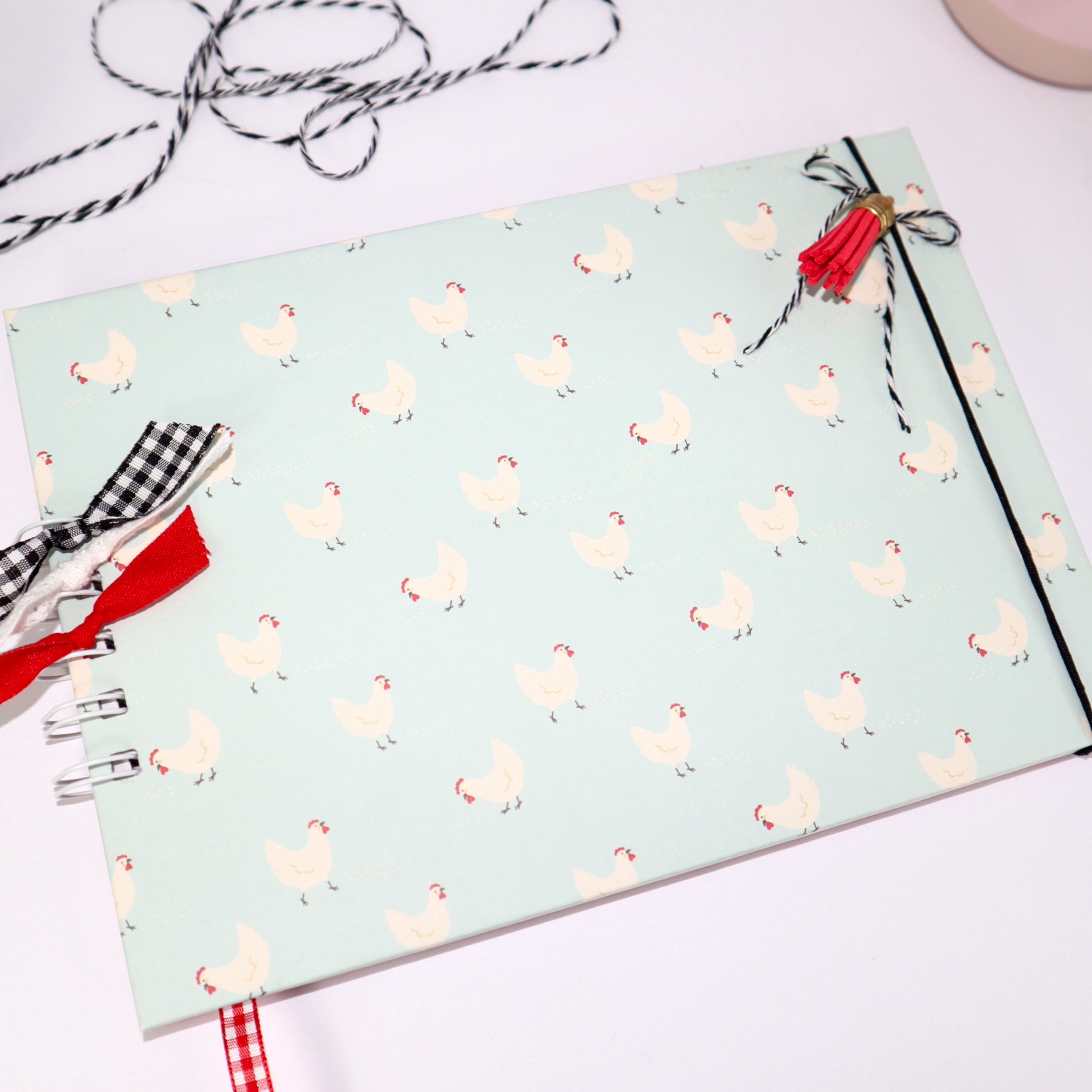 Caderno azul claro com padrão de galinhas brancas e laços decorativos