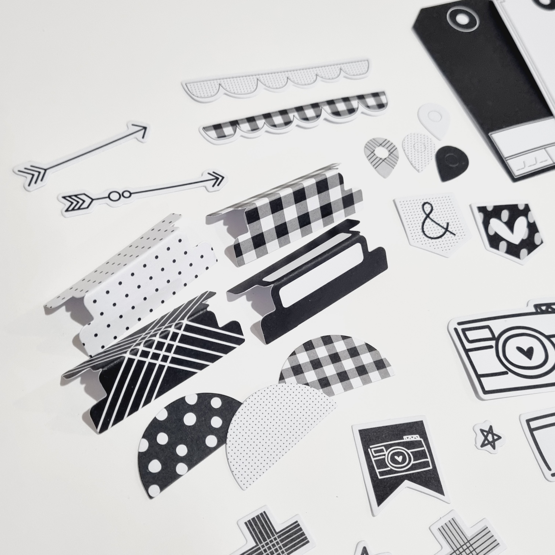 Elementos decorativos de papel em preto e branco com diferentes padrões sobre fundo branco