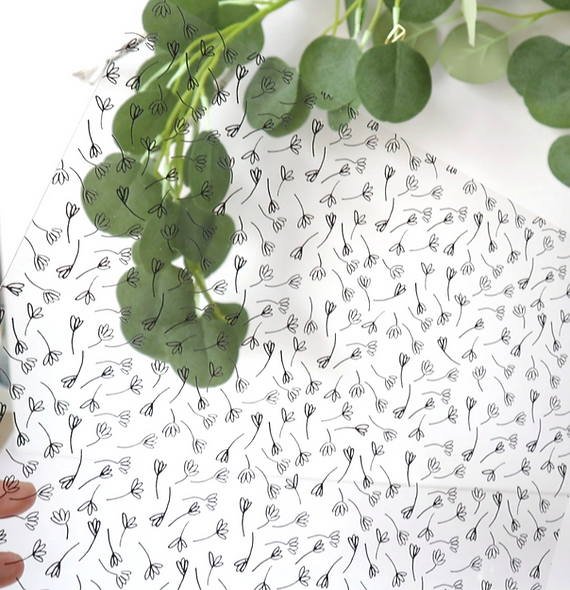 Folha transparente com padrão de raminhos pretos e folhas verdes ao fundo