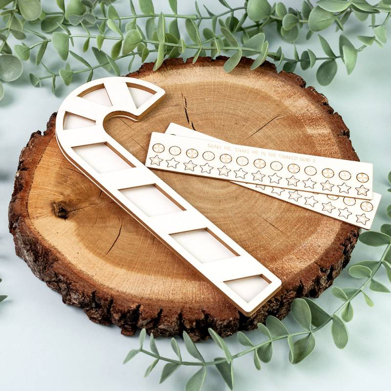 Régua branca em forma de bastão de Natal sobre tronco de madeira com etiquetas de estrelas e círculos ao lado