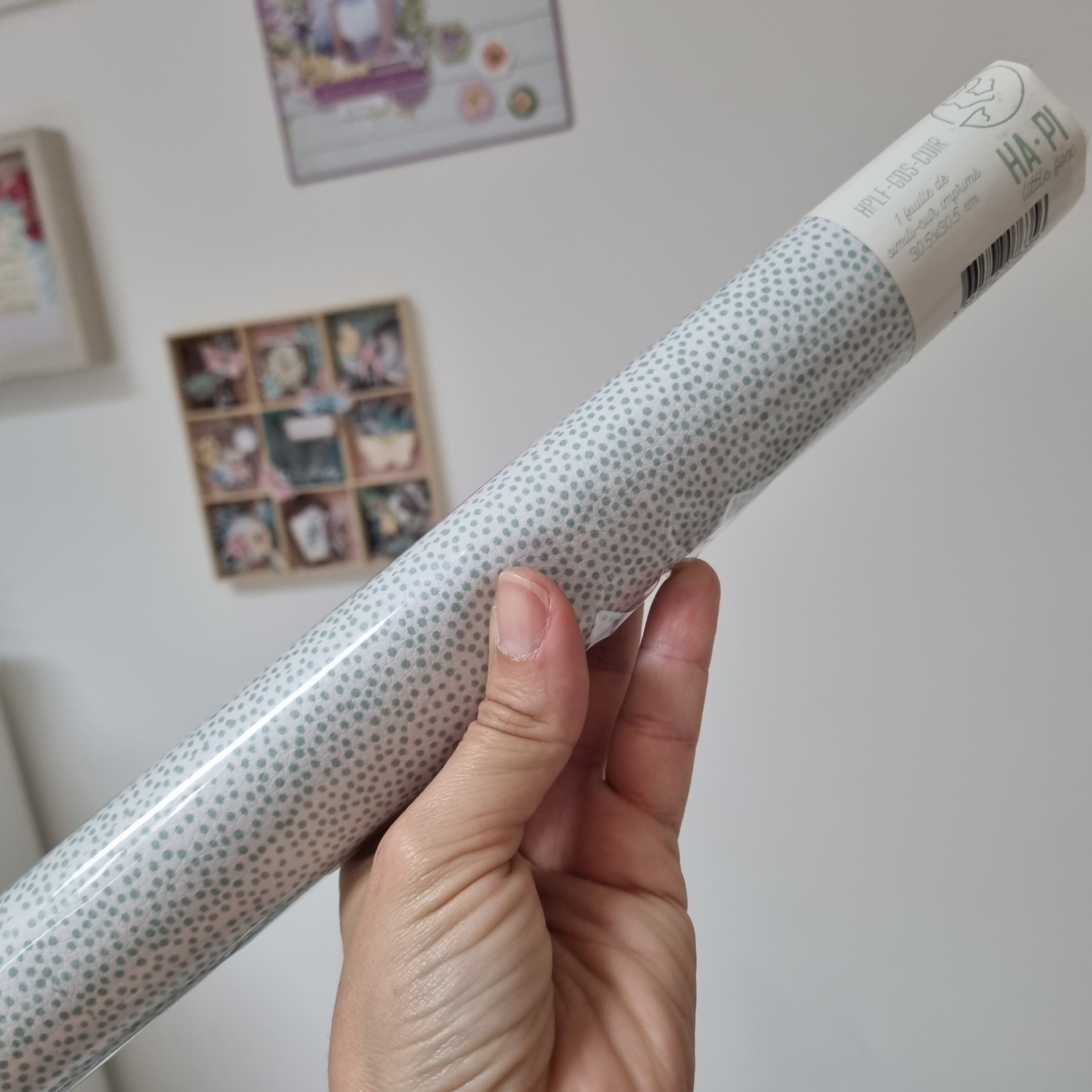Rolo de papel decorativo cinza e branco com etiqueta de marca HA-PI segurado por mão humana