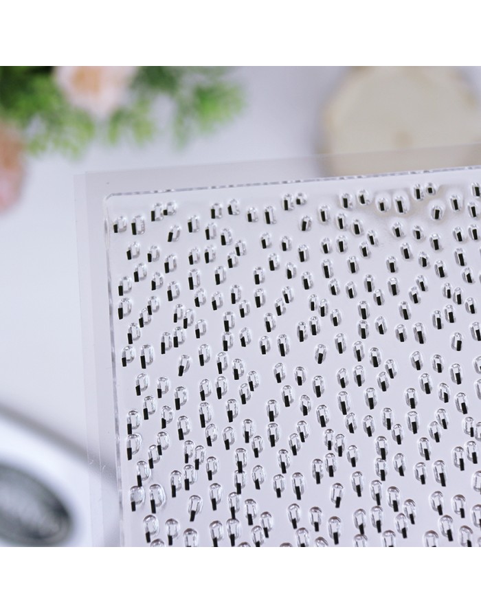 Folha transparente com pequenos elementos pretos e brancos dispostos em padrão repetitivo