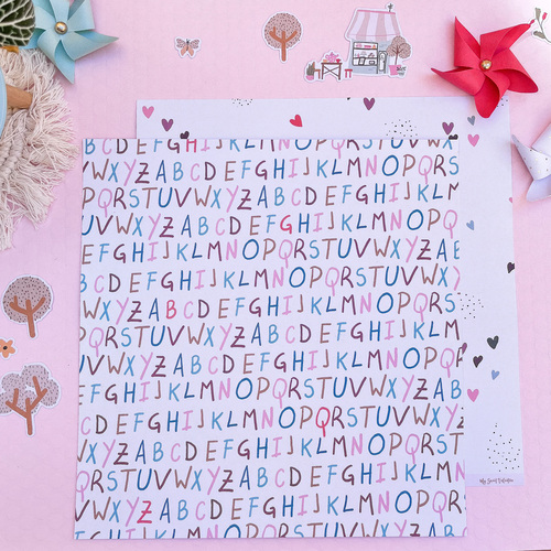 Folha com padrão colorido de letras do alfabeto sobre fundo rosa decorado com desenhos pequenos e dois cata-ventos de papel.