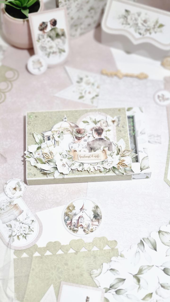 Elementos de papelaria decorativa verdes e brancos com ilustrações florais e casal, incluindo caixa e botões com imagens religiosas.