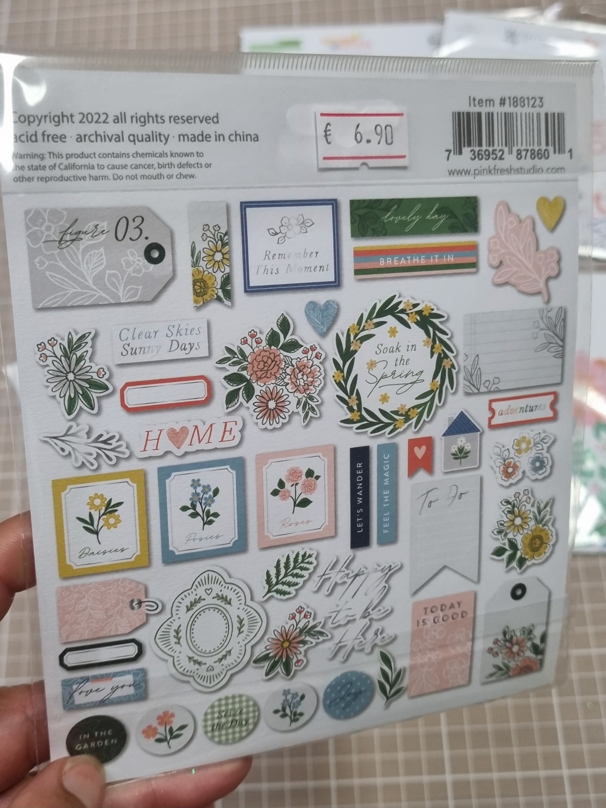 Folha de autocolantes decorativos florais coloridos com textos em inglês em embalagem plástica.