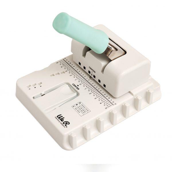 Máquina perfuradora manual branca com alavanca azul clara e escala de medidas.