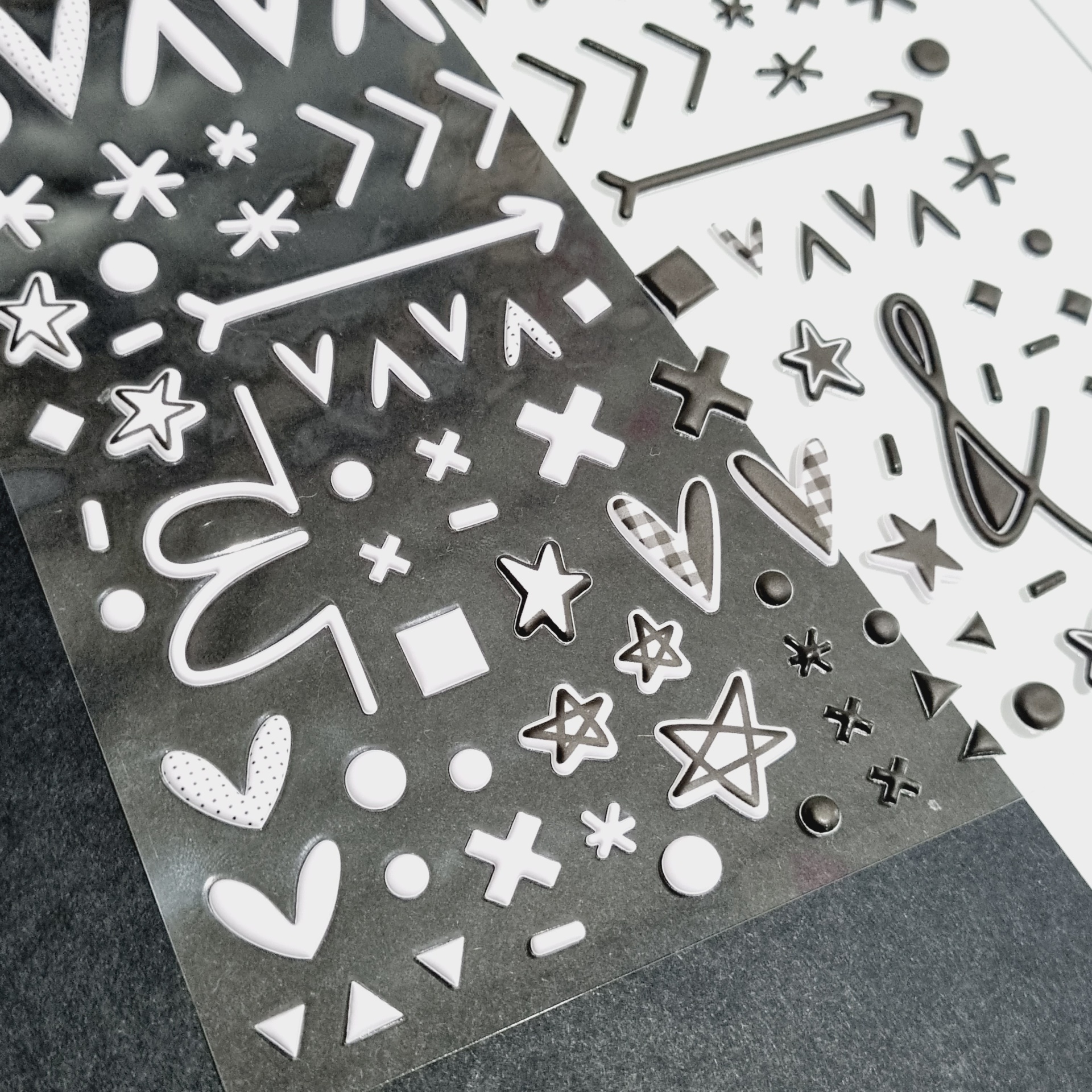 Folhas transparentes com autocolantes pretos e brancos de várias formas geométricas e símbolos
