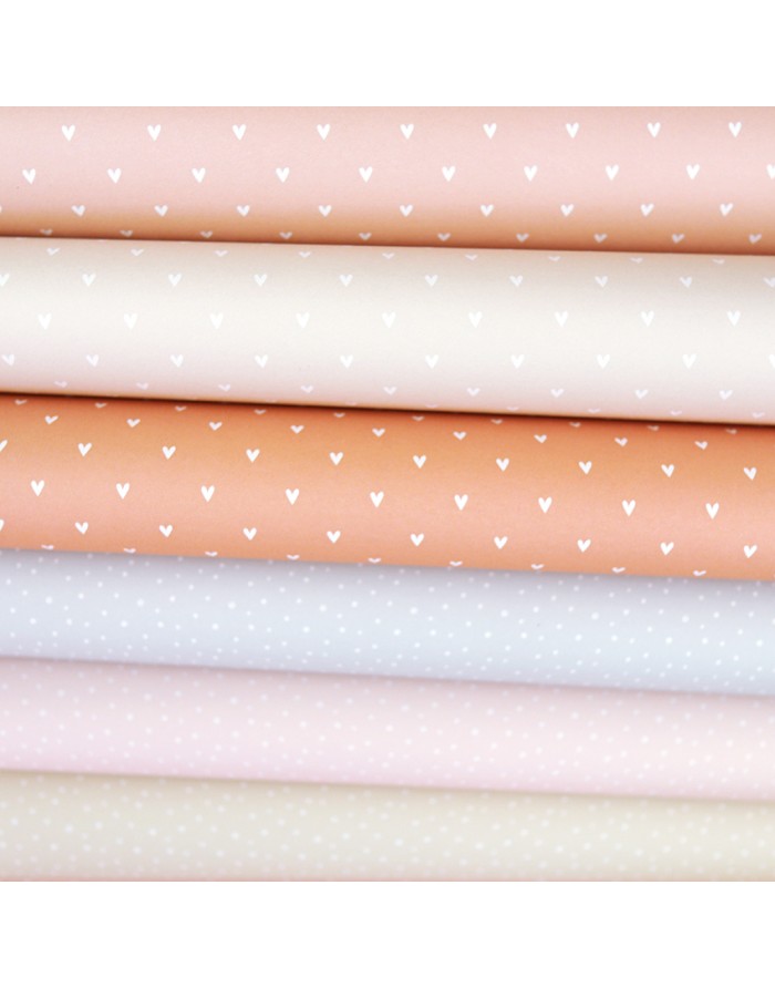 Tecidos em tons pastel com padrões de corações e pontos brancos dobrados
