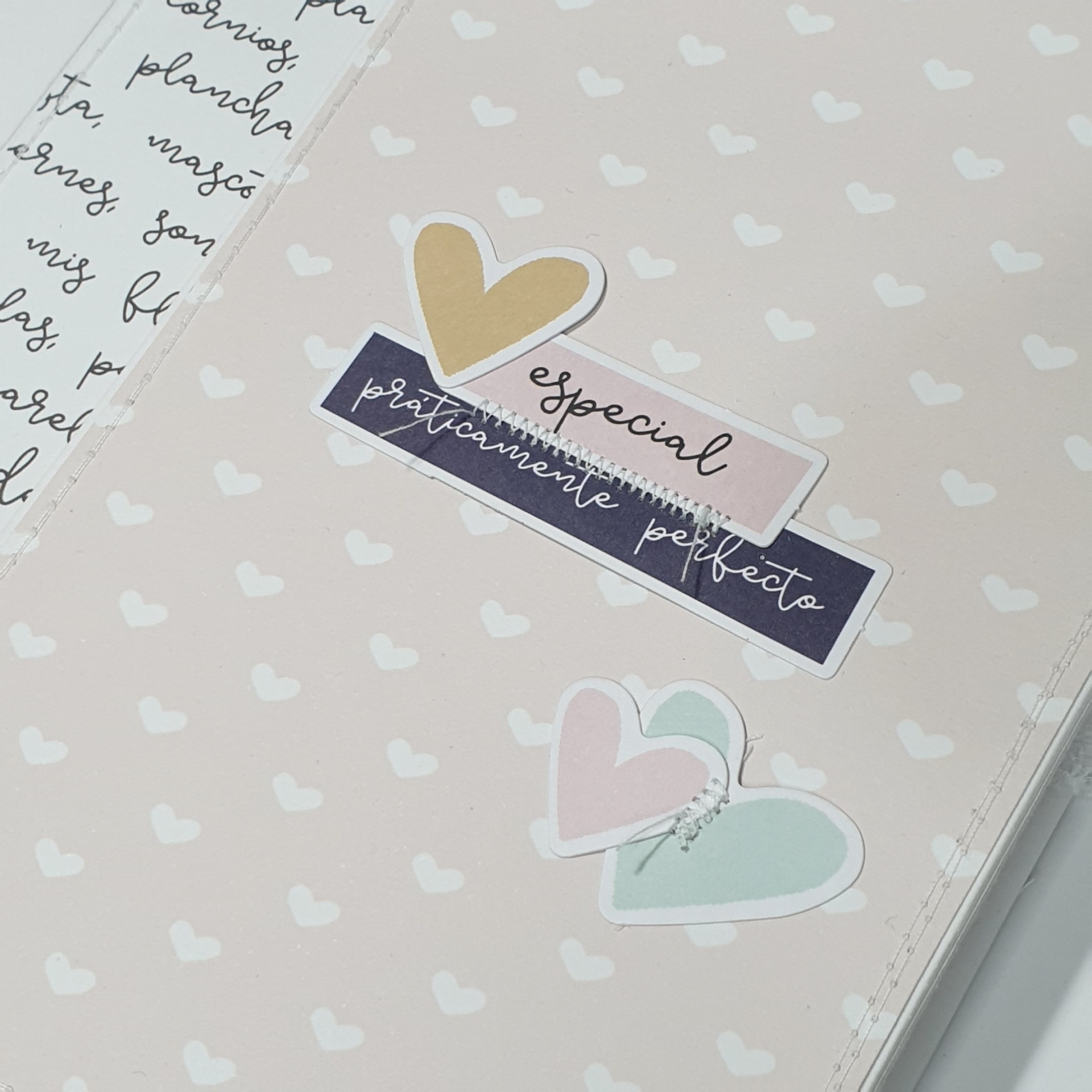 Caderno com capa bege, corações brancos e etiquetas com texto 'especial' e 'praticamente perfeito'.