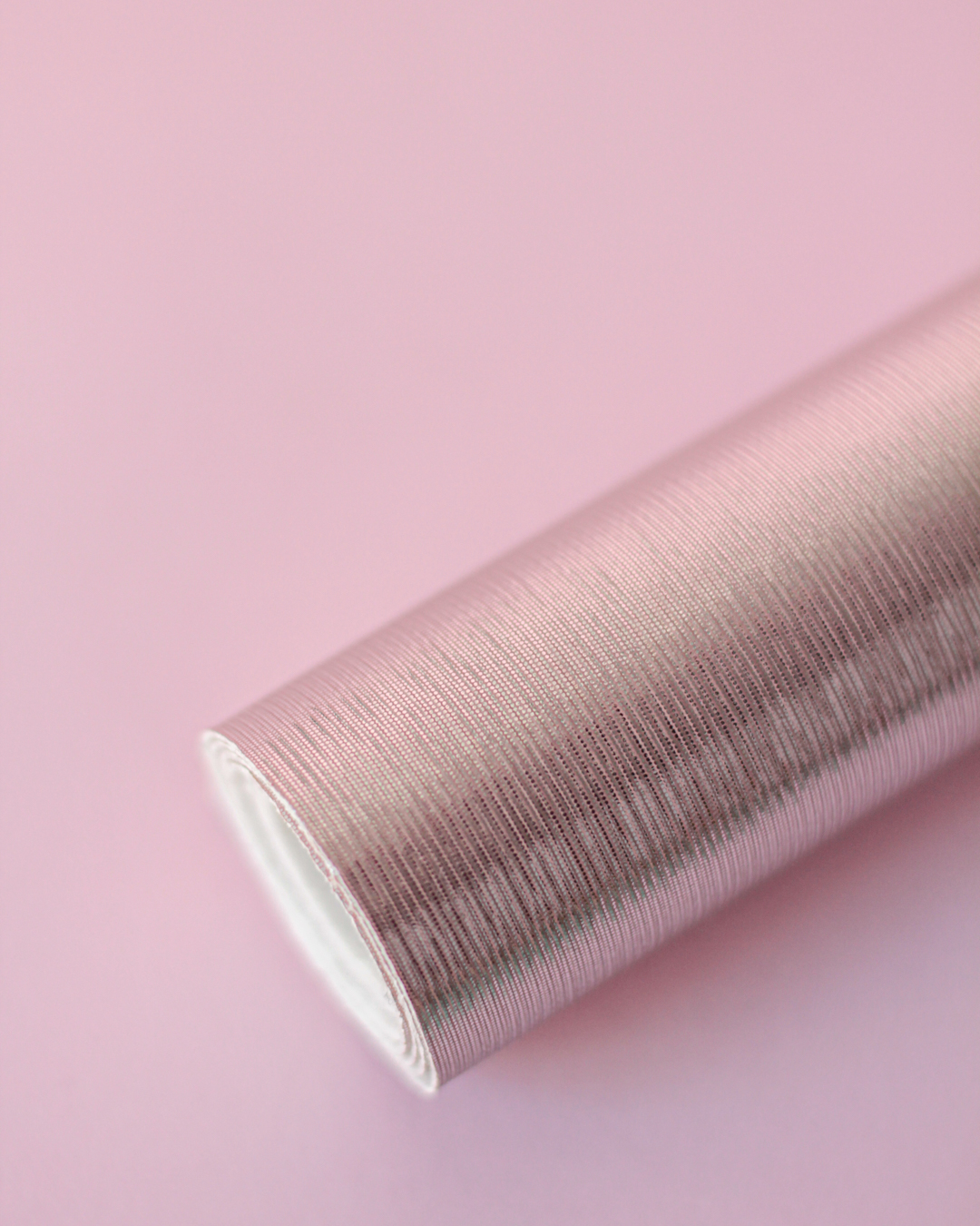 Rolo de papel de parede rosa com textura fina sobre fundo rosa claro
