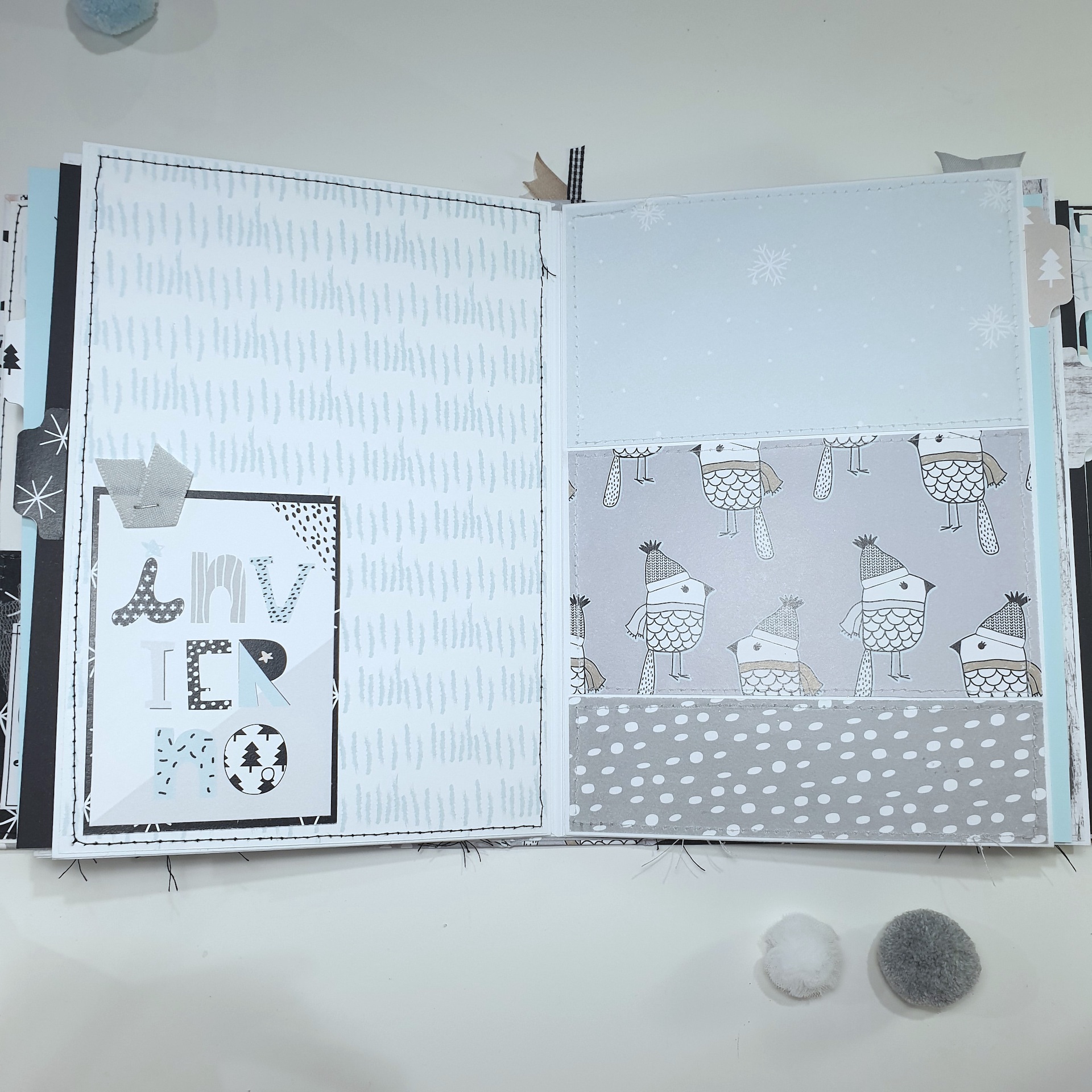 Livro de recortes aberto com páginas decoradas em tons cinza, branco e azul claro