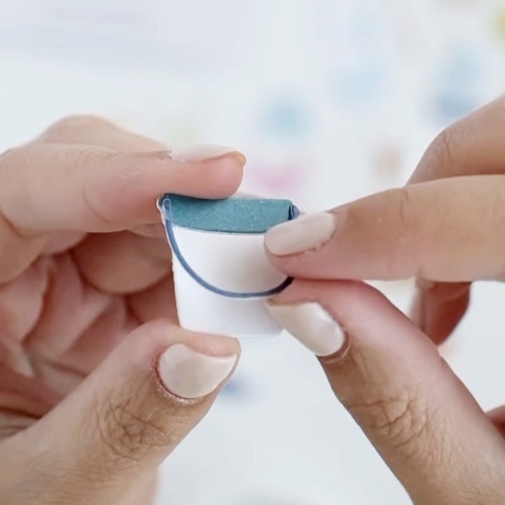 Mãos segurando um pequeno produto branco e azul