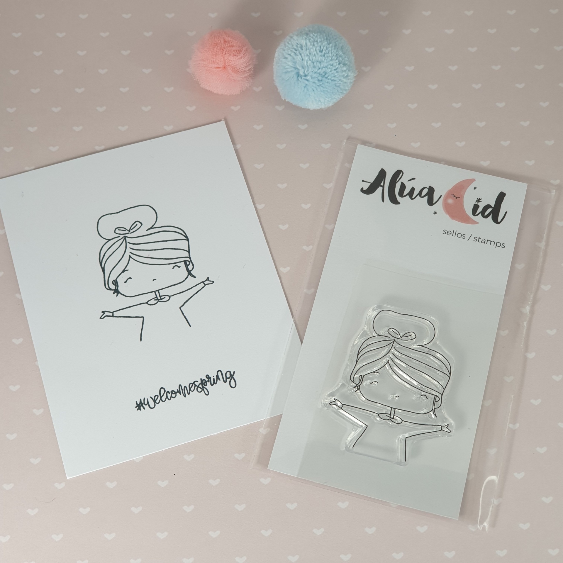 Carimbo e cartão com desenho de menina, pompons cor de rosa e azul sobre fundo cor-de-rosa com corações