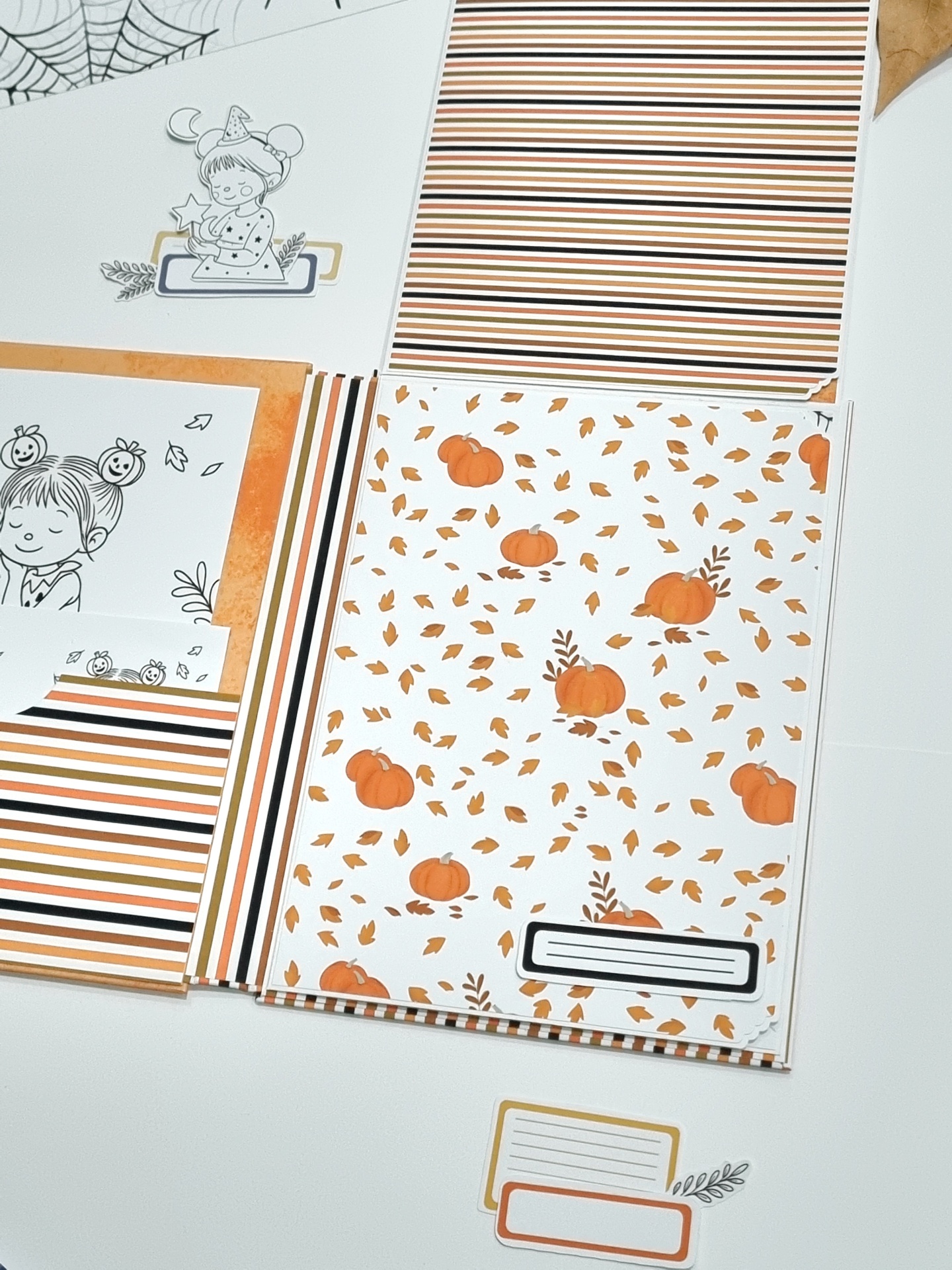 Folhas de papel decorativo com motivos de abóboras, folhas, riscas e ilustrações infantis.