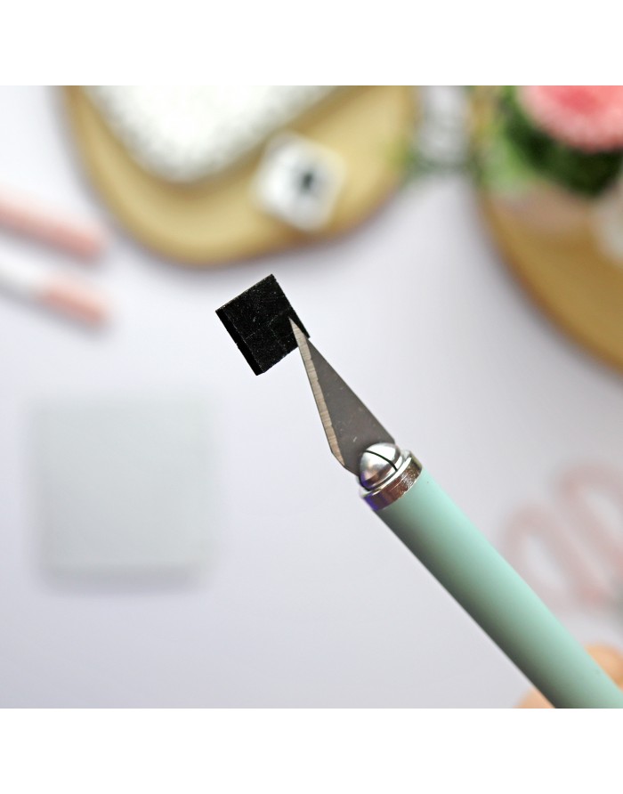 Estilete com lâmina triangular segurando um quadrado preto