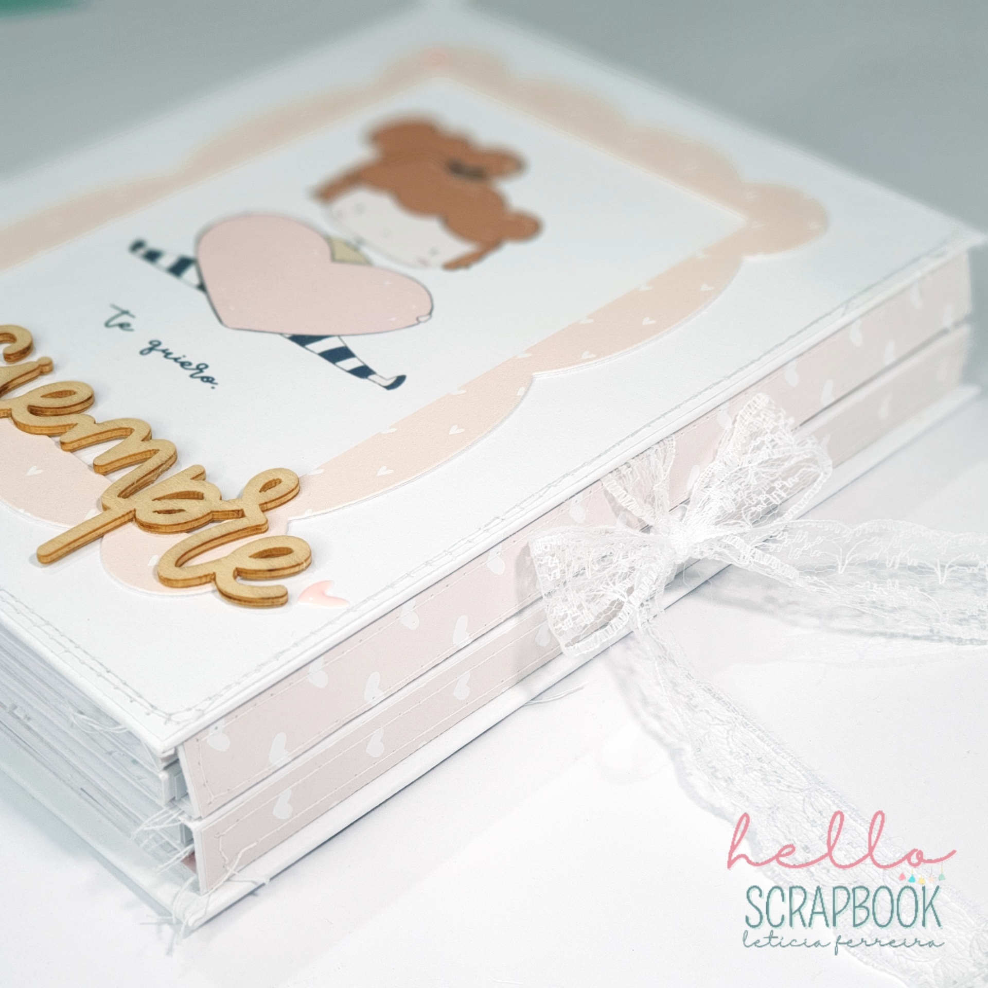 Álbum de scrapbook decorado com cão e coração, texto em espanhol e laço de renda branca.