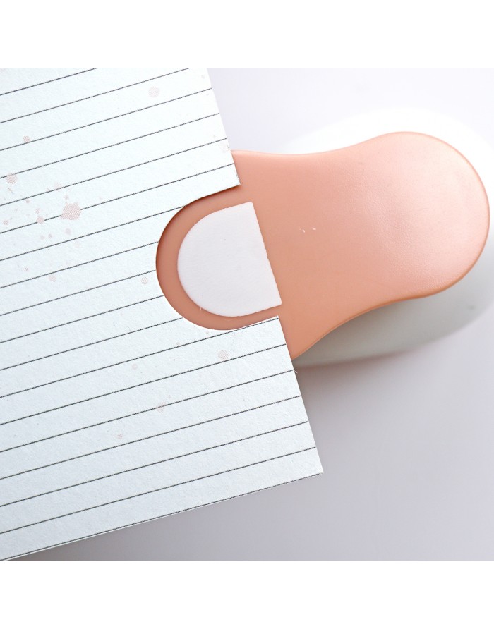 Recortador de papel com pega cor de pele e disco branco junto a folha de papel com linhas pretas