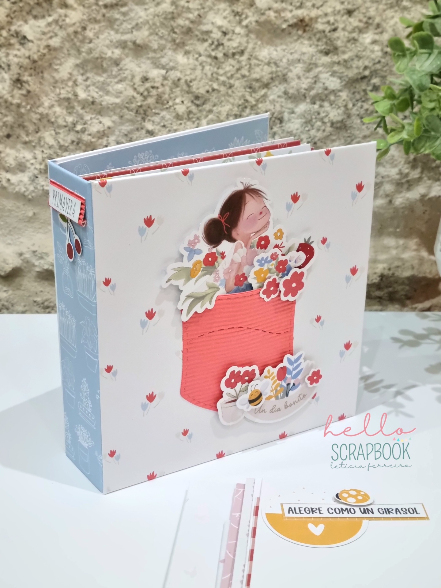 Álbum de scrapbook decorado com bolso vermelho e flores em fundo branco com padrão de pequenas flores vermelhas