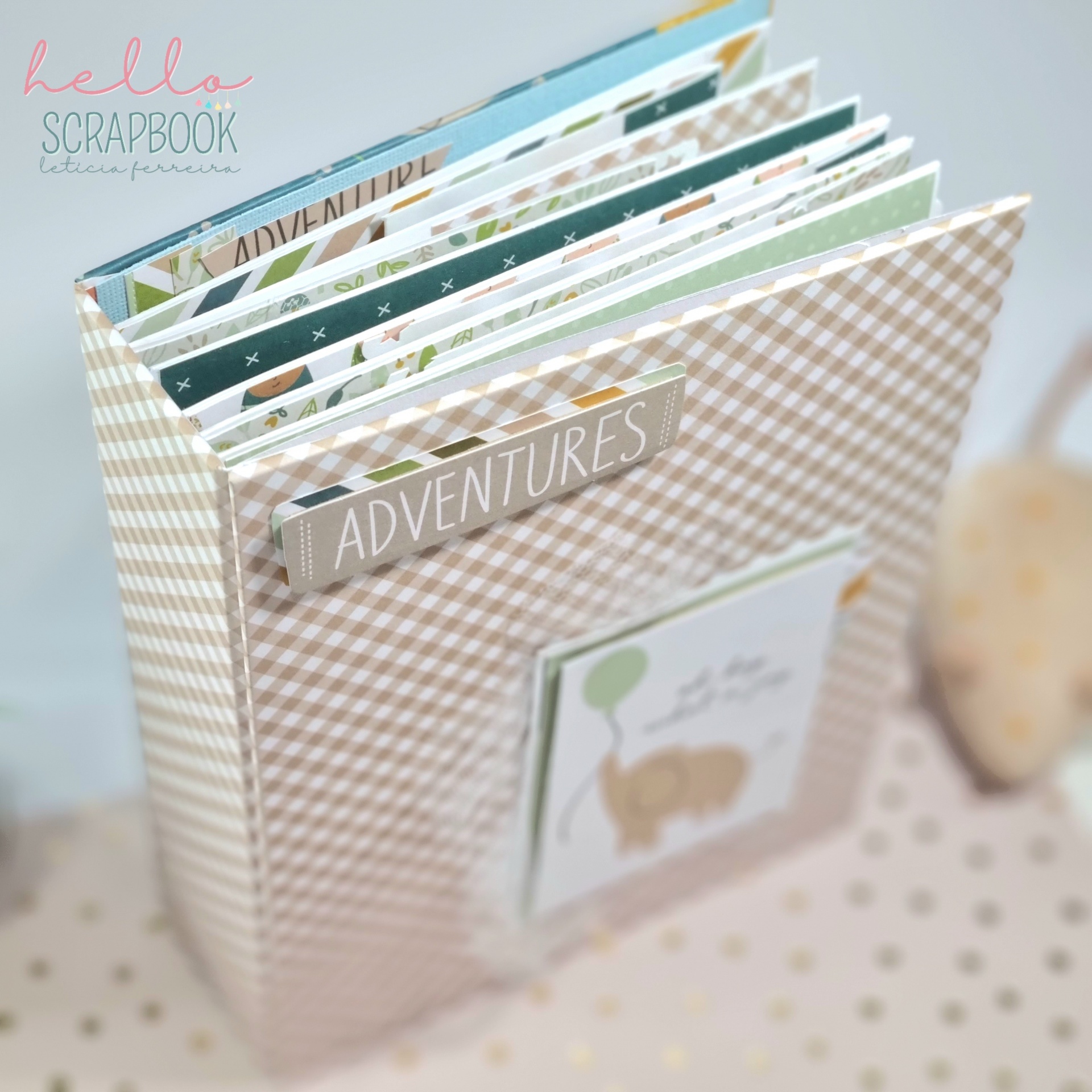 Álbum de scrapbook em padrão xadrez bege com título ADVENTURES
