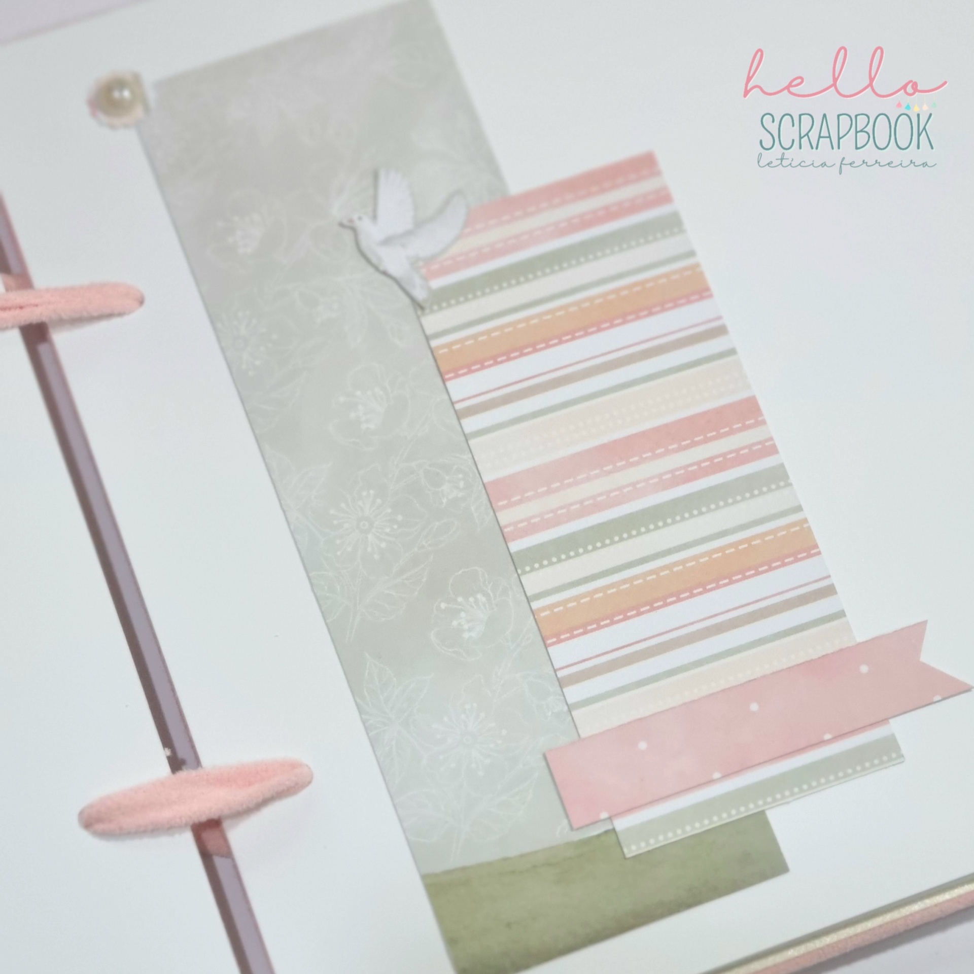 Scrapbook branco com elementos decorativos às riscas em tons pastel e elásticos cor-de-rosa