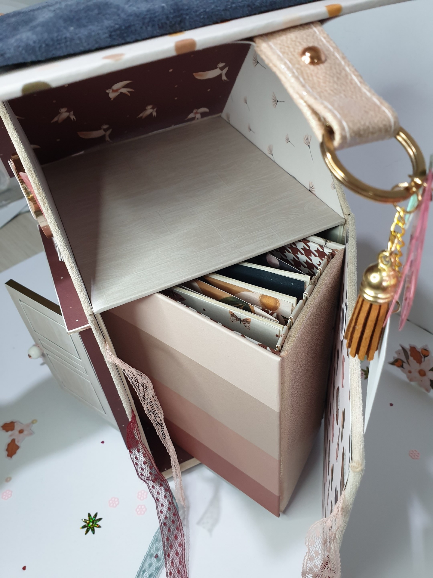 Caixa decorativa com padrões de pássaros e organizador interior com divisórias em tons castanhos e bege