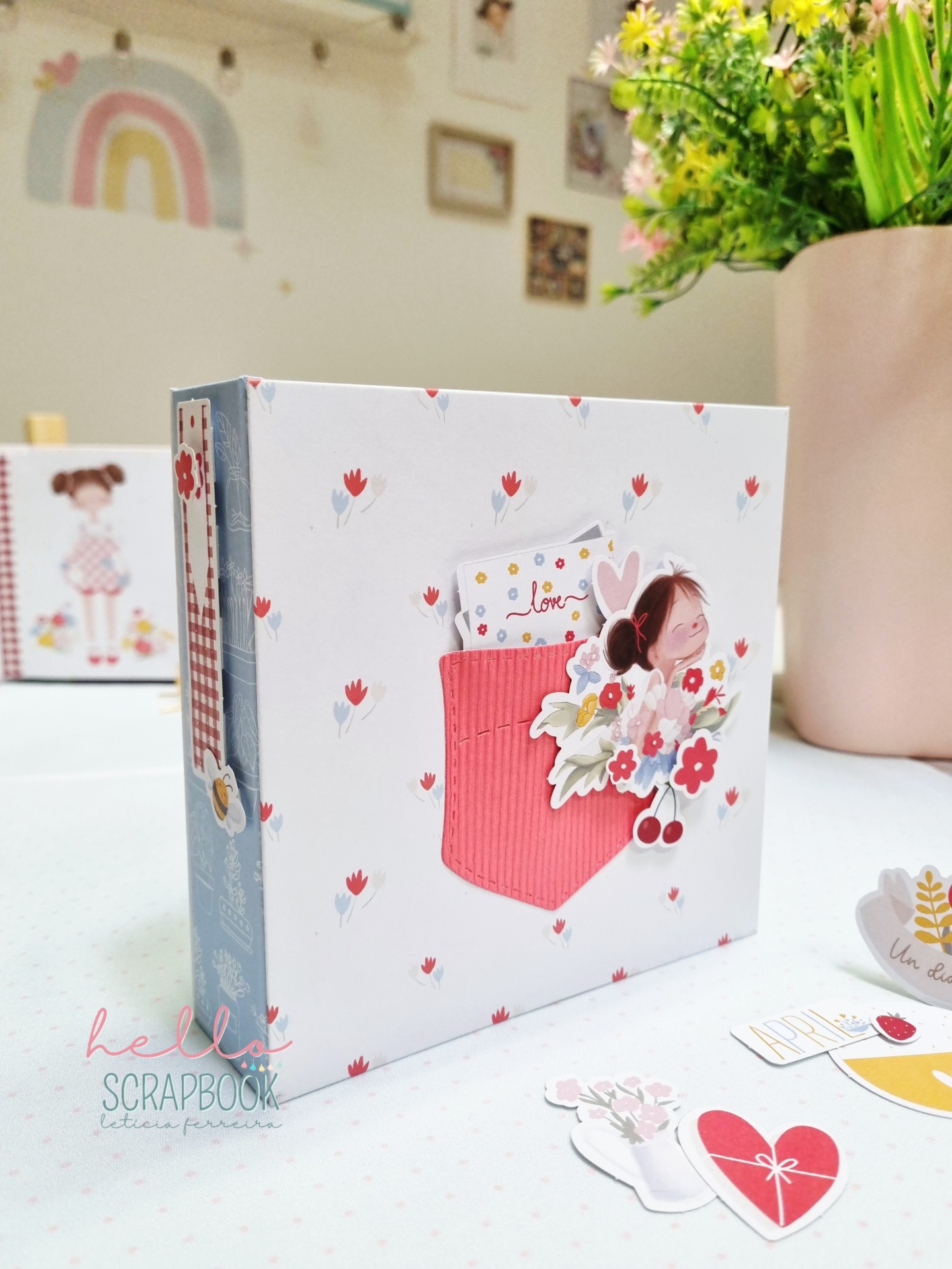 Álbum de scrapbook com design floral e recortes decorativos sobre mesa branca