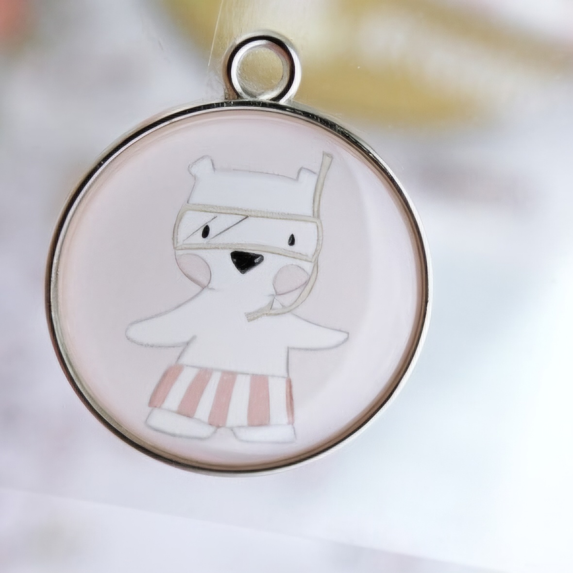 Pingente redondo com desenho de urso branco em calções riscas rosa e branco