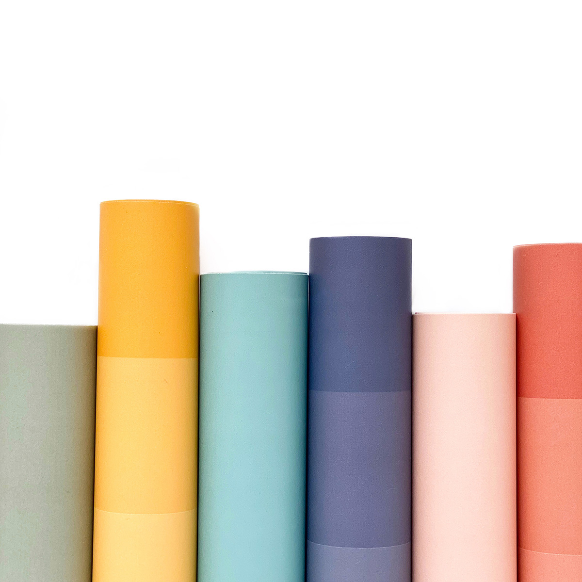 Seis rolos coloridos de papel ou tecido em fila sobre fundo branco.