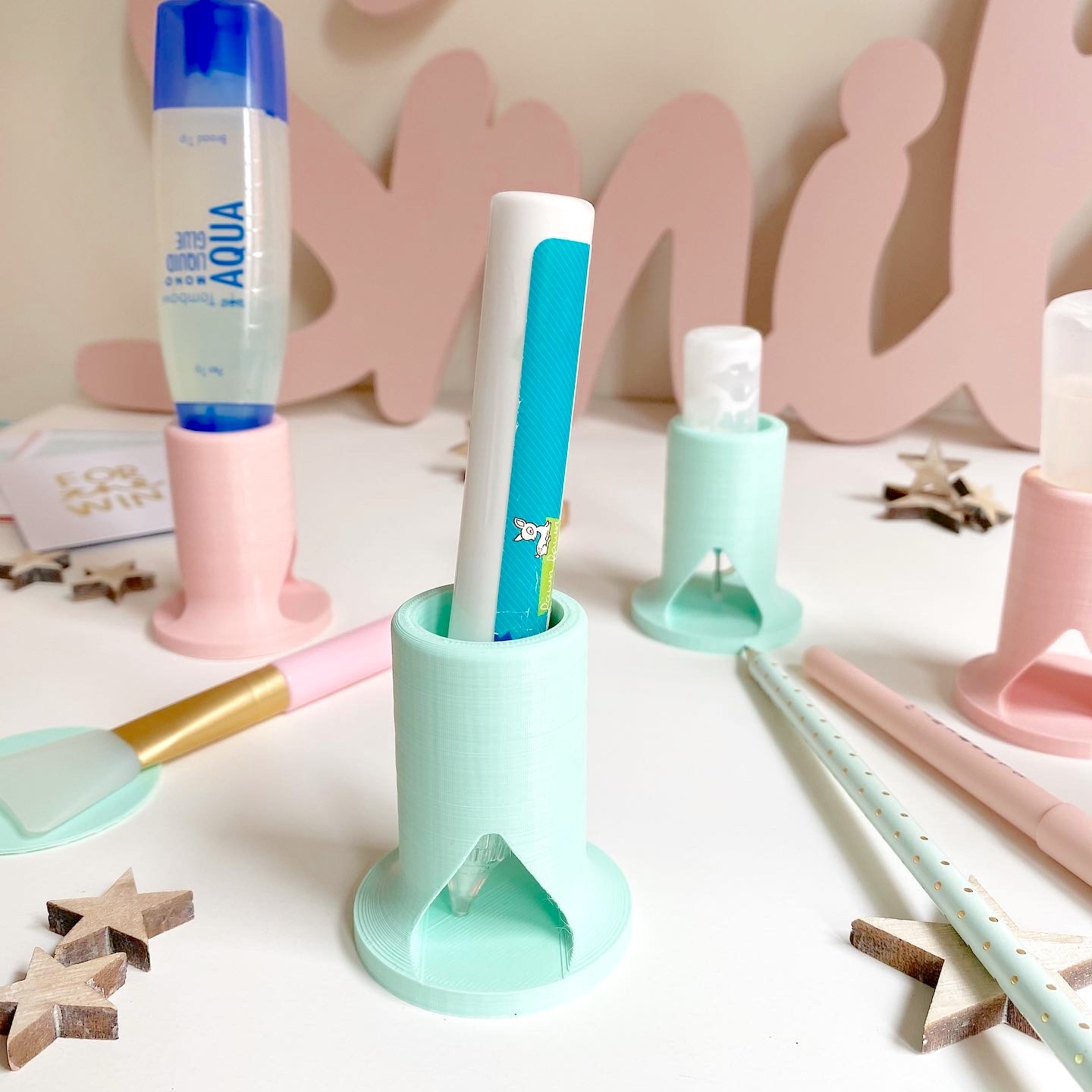 Suportes plásticos em tons pastel com objetos de maquilhagem e decoração em fundo branco