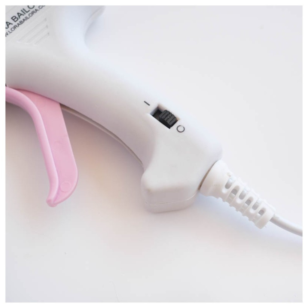 Pistola de cola quente branca com gatilho cor-de-rosa e interruptor