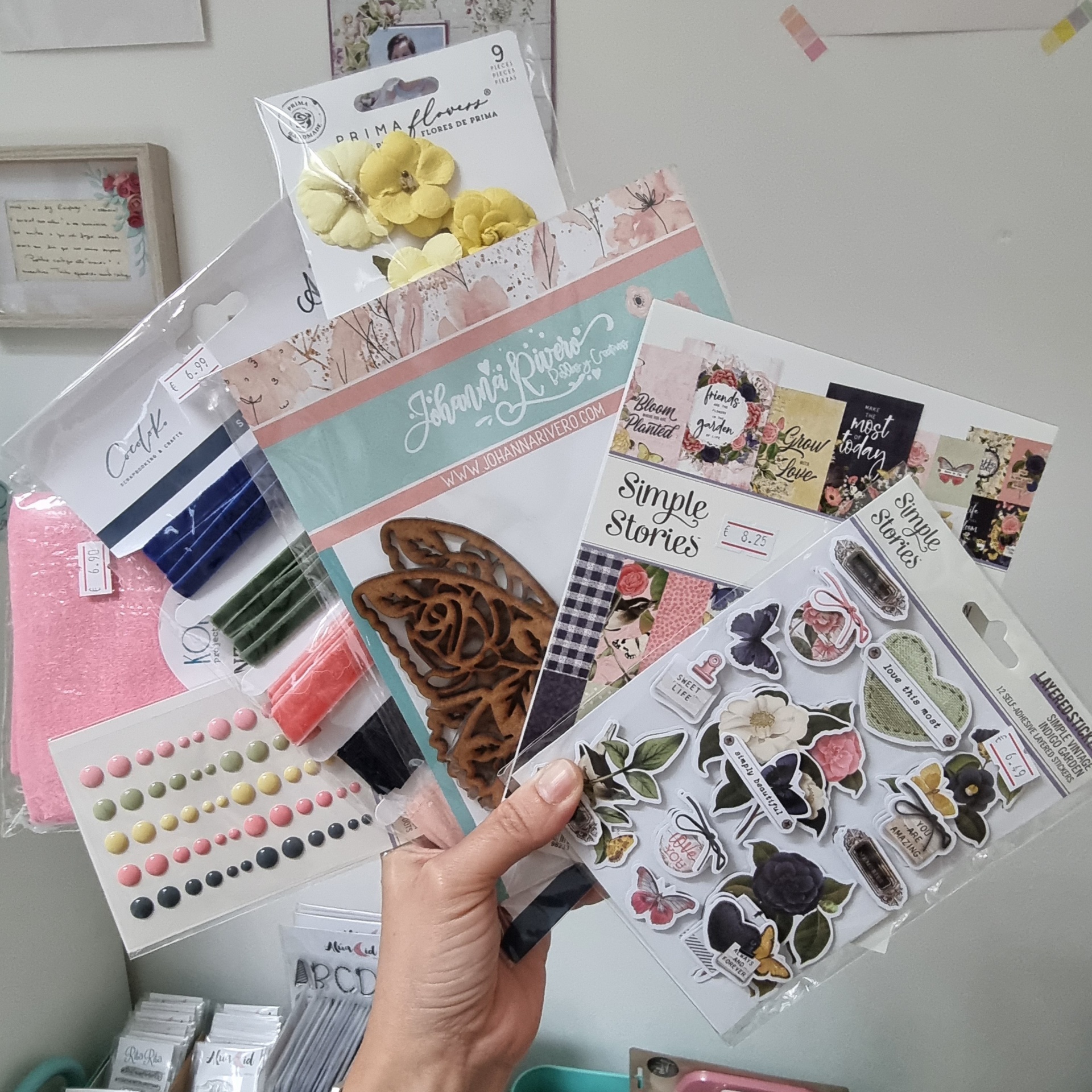 Artigos para scrapbooking como flores artificiais amarelas e adesivos decorativos em embalagem plástica