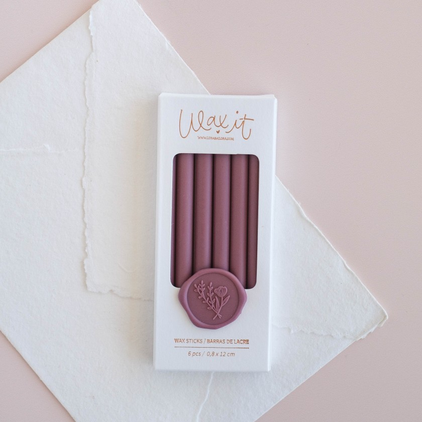 Caixa branca com 6 varetas de cera violeta e selo violeta com desenho floral em fundo rosa claro