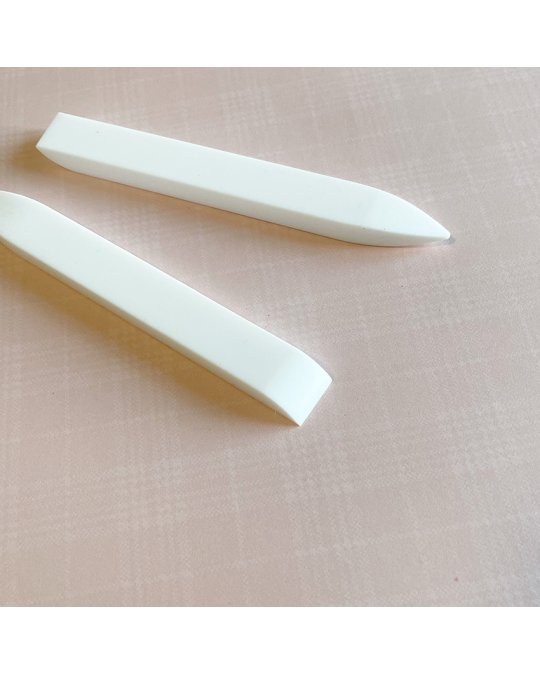 Duas ferramentas brancas alongadas sobre tecido rosa claro quadriculado