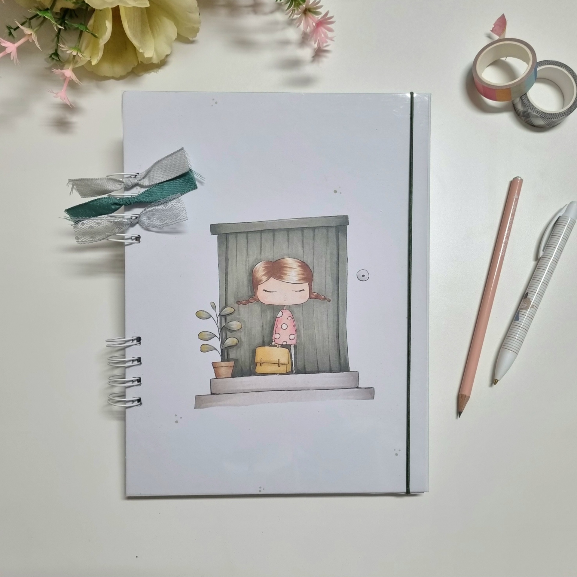 Caderno com capa branca, ilustração de menina, alças elásticas, lápis, caneta, fitas adesivas e flores