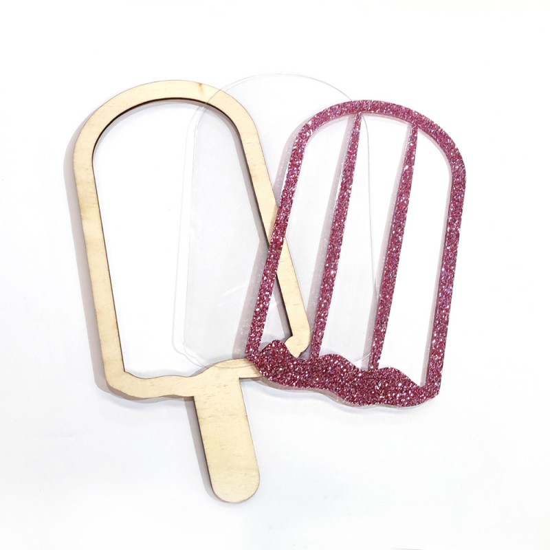 Molde para gelados em madeira, plástico transparente e glitter rosa em forma de pauzinho.
