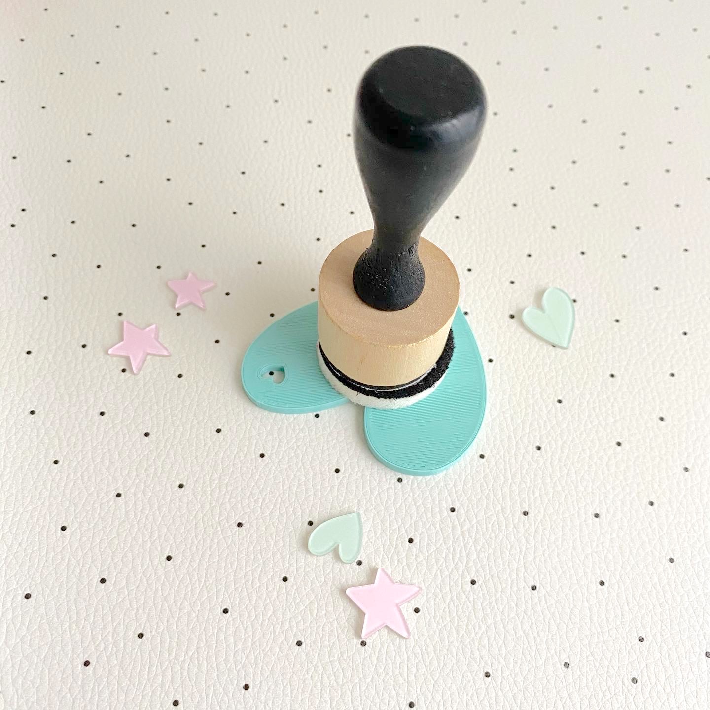 Carimbo de borracha com punho preto e base em madeira com estrelas e corações ao redor
